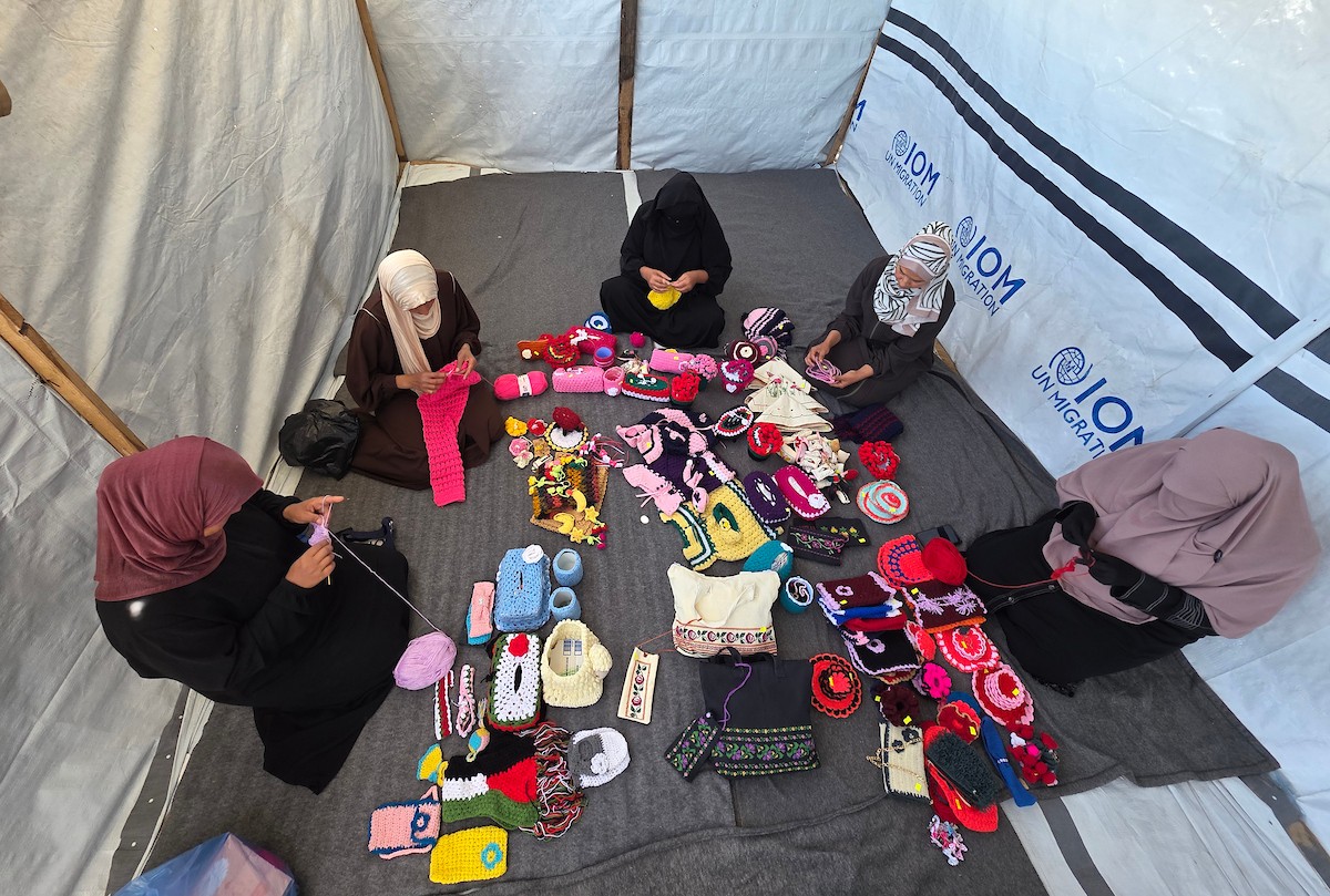 أرامل فلسطينيات يعملن على حياكة المشغولات الصوفية داخل خيمة في مخيم البركة للأيتام بمنطقة مواصي في خان يونس جنوب قطاع غزة، في 11 مايو/أيار 2026، سعياً منهن لتأمين دخل لإعالة أطفالهن بعد استشهاد أزواجهن في الحرب. (صورة: طارق محمد)