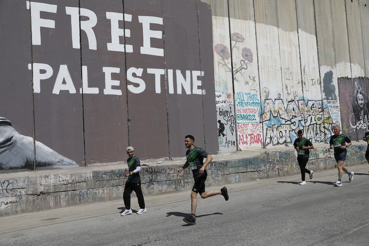 تُظهر الصورة عدائين مشاركين في ماراثون فلسطين الدولي وهم يركضون في شوارع بيت لحم، في مشهد يجمع بين الطابع الرياضي للحدث ورمزيته السياسية والإنسانية المرتبطة بحرية الحركة، 8 مايو/أيار 2026.عدسة: مأمون وزواز.