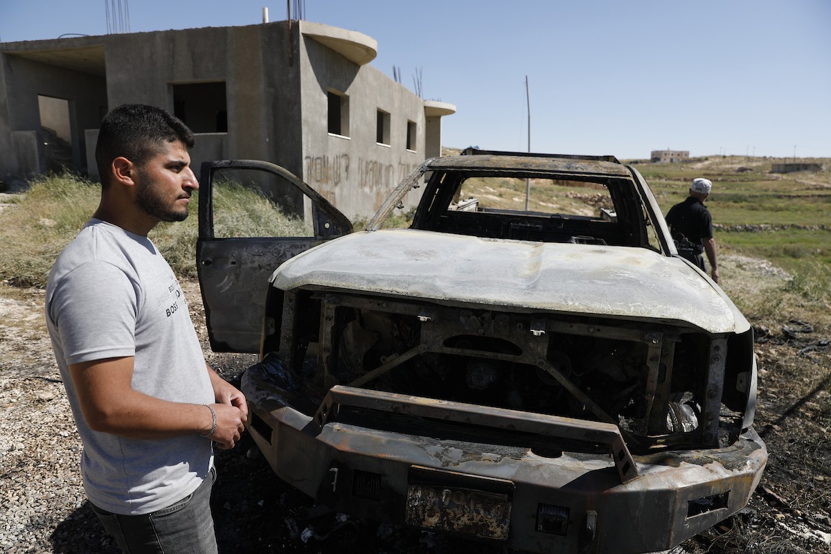 يتفقد فلسطينيون مركبةً تضررت بعد أن أضرم فيها مستوطنون إسرائيليون النار في وادي الرحيم قرب بلدة يطا، جنوب الخليل في الضفة الغربية، في الأول من مايو/أيار 2026.(صورة: مأمون وزواز)