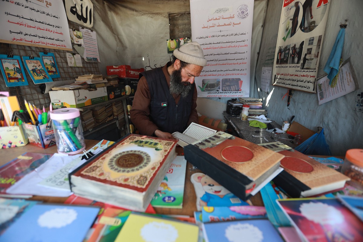 المسنّ الفلسطيني رفعت جبر يرمم نسخ تالفة من المصحف الشريف، عُثر عليها بين أنقاض المساجد والمنازل التي دُمّرت خلال الهجمات الإسرائيلية في مدينة غزة، 5 مايو/أيار 2026 (صورة: عمر أشتوي)