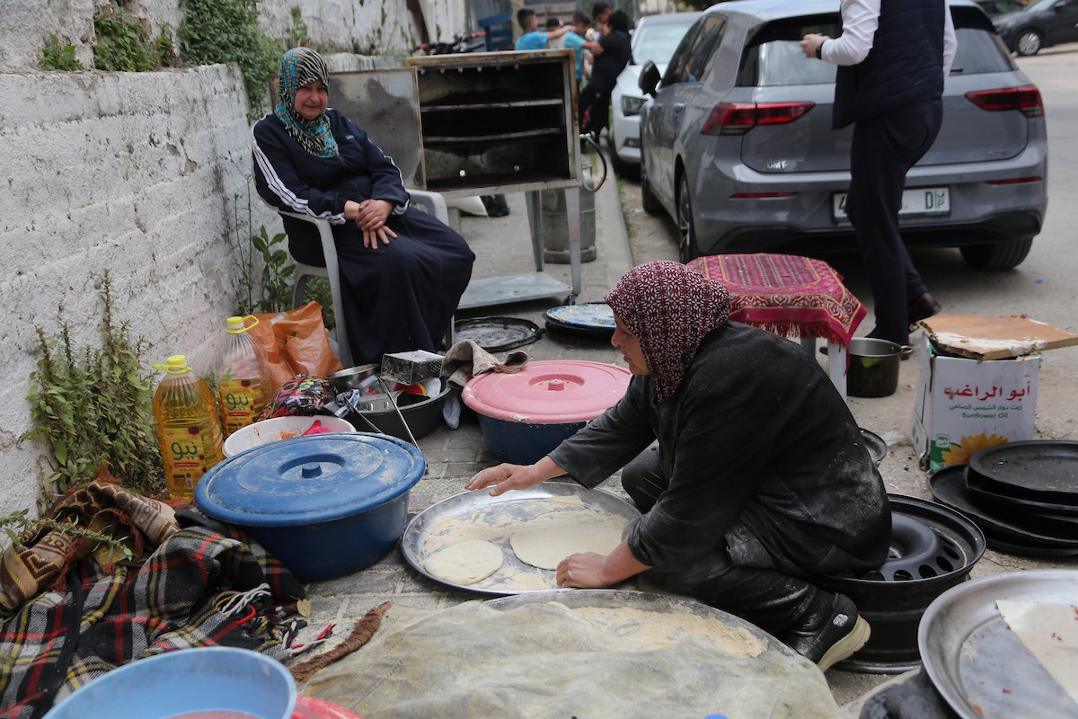 امرأة فلسطينية تُعدّ الخبز على نار الحطب في شارع رئيسي بنابلس شمال الضفة الغربية، 2 مايو/أيار 2026، خلال معرض 