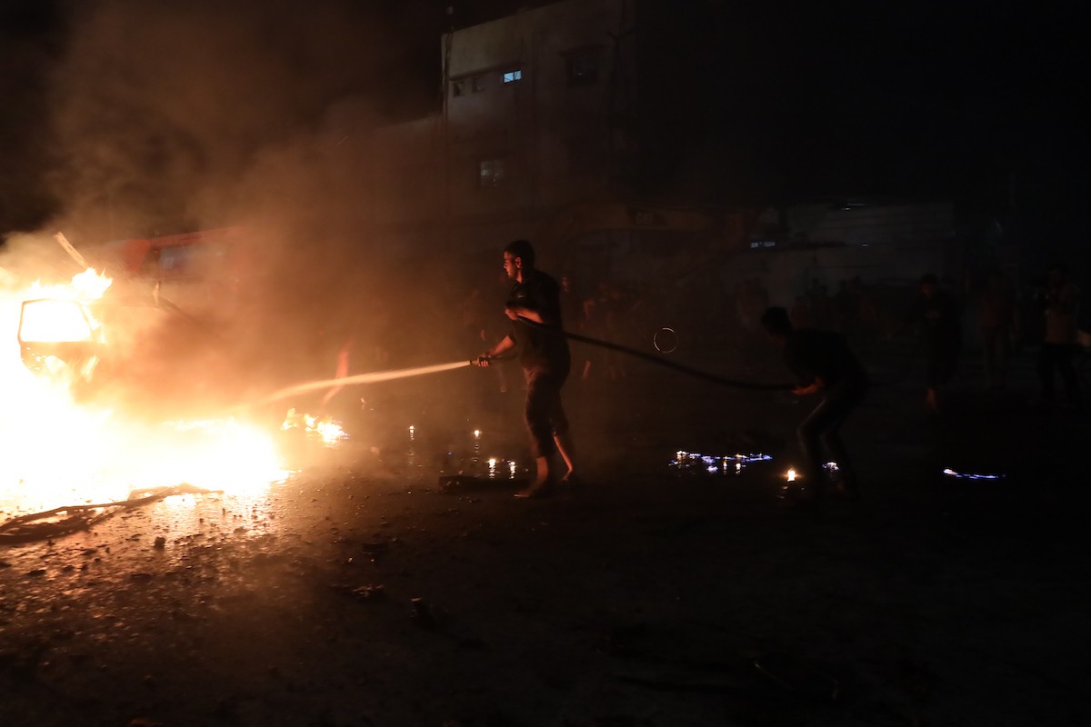 فلسطينيون يعملون على إخماد حريق اندلع في سيارة استُهدفت بغارة إسرائيلية في حي الرمال بمدينة غزة، الجمعة 15 مايو/أيار 2026. صورة: عمر أشتوي.
