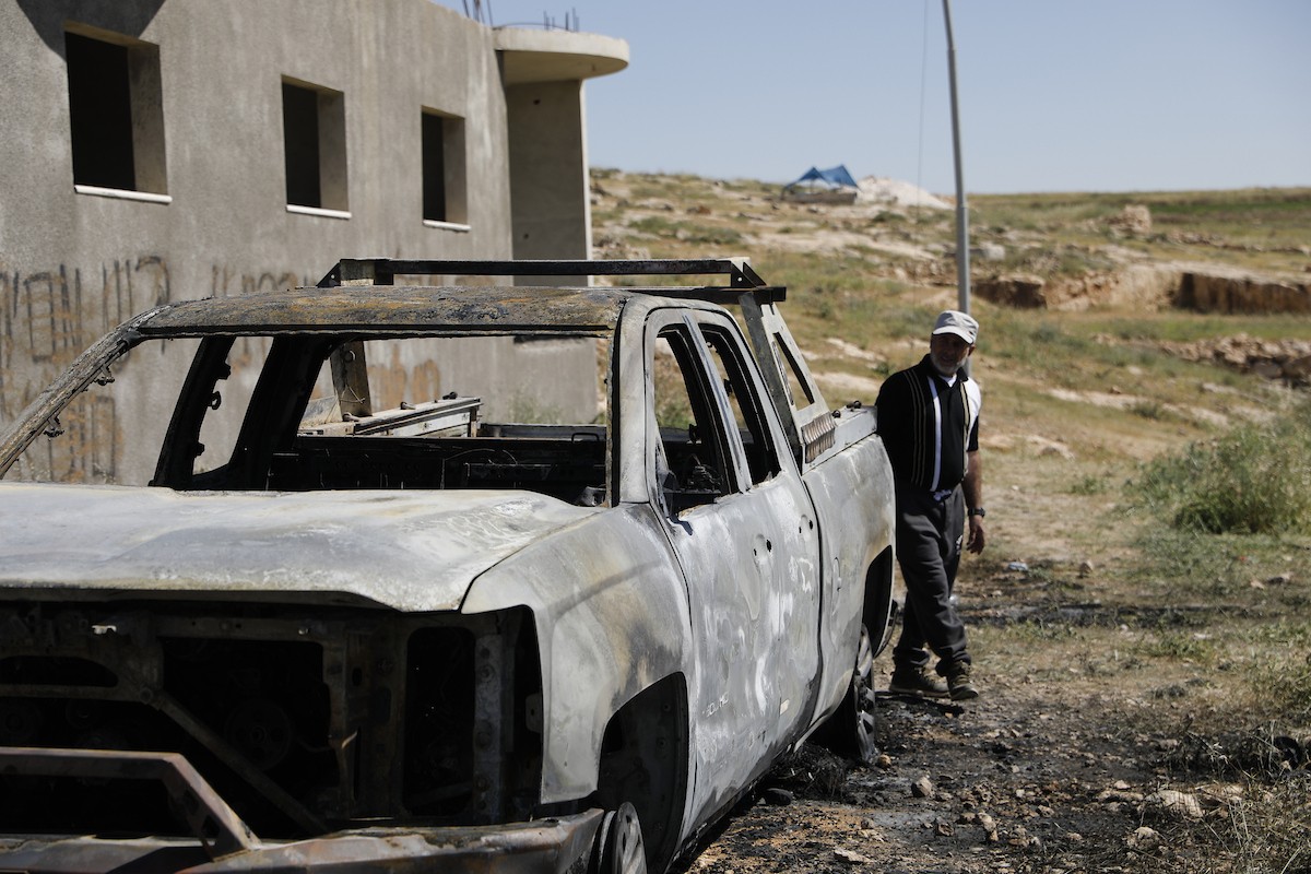 يتفقد فلسطينيون مركبةً تضررت بعد أن أضرم فيها مستوطنون إسرائيليون النار في وادي الرحيم قرب بلدة يطا، جنوب الخليل في الضفة الغربية، في الأول من مايو/أيار 2026.(صورة: مأمون وزواز)