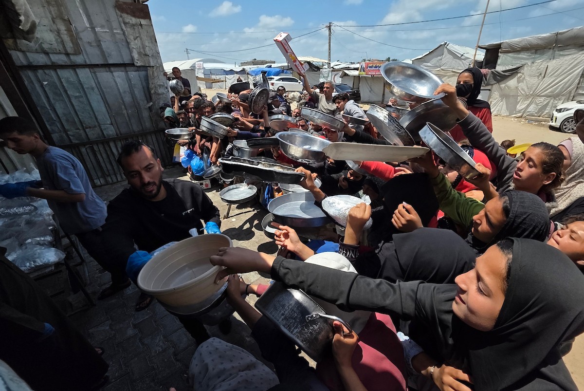تُظهر الصورة نازحين فلسطينيين متجمعين حول نقطة توزيع طعام في خان يونس جنوب قطاع غزة، حيث ينتظر رجال ونساء وأطفال الحصول على وجبات من مطبخ خيري وسط ظروف إنسانية صعبة،  8 مايو/أيار 2026. عدسة : طارق محمد