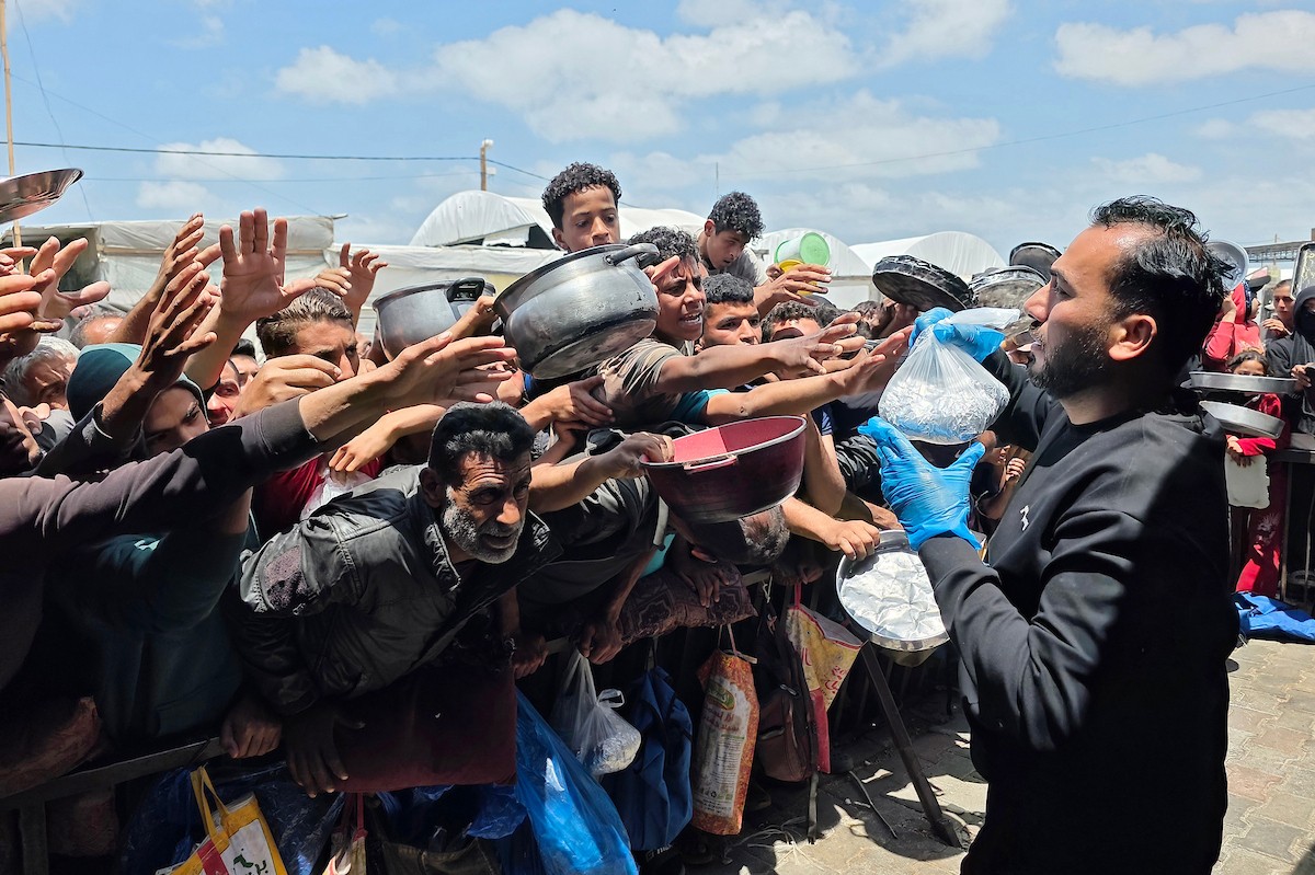 تُظهر الصورة نازحين فلسطينيين متجمعين حول نقطة توزيع طعام في خان يونس جنوب قطاع غزة، حيث ينتظر رجال ونساء وأطفال الحصول على وجبات من مطبخ خيري وسط ظروف إنسانية صعبة،  8 مايو/أيار 2026. عدسة : طارق محمد
