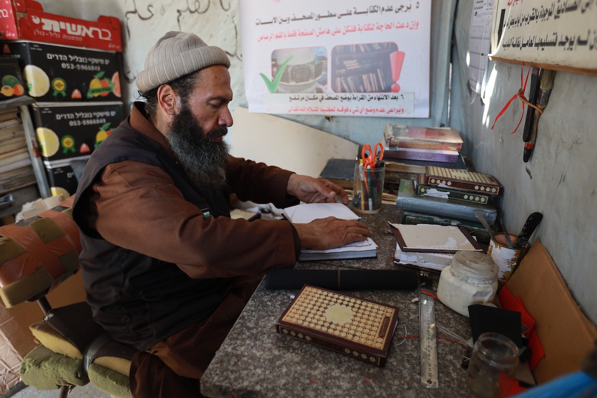 المسنّ الفلسطيني رفعت جبر يرمم نسخ تالفة من المصحف الشريف، عُثر عليها بين أنقاض المساجد والمنازل التي دُمّرت خلال الهجمات الإسرائيلية في مدينة غزة، 5 مايو/أيار 2026 (صورة: عمر أشتوي)