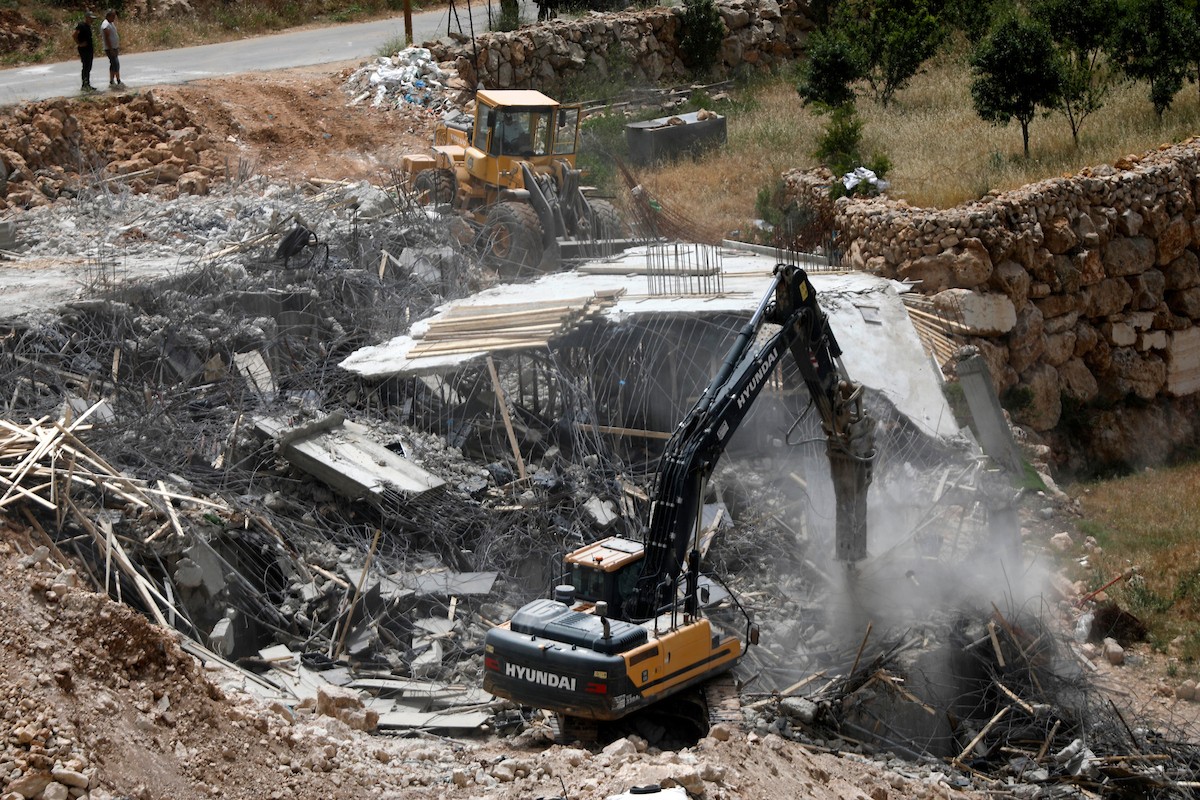 جرافات إسرائيلية تهدم مبنى سكنياً فلسطينياً قيد الإنشاء في بلدة الولجة غرب بيت لحم، في 18 مايو/أيار 2026، وسط انتشار قوات الاحتلال وتجمّع الأهالي لمتابعة عملية الهدم. الصورة: مأمون وزواز