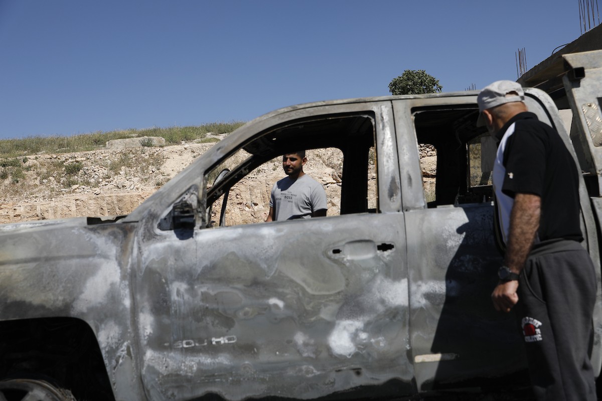 يتفقد فلسطينيون مركبةً تضررت بعد أن أضرم فيها مستوطنون إسرائيليون النار في وادي الرحيم قرب بلدة يطا، جنوب الخليل في الضفة الغربية، في الأول من مايو/أيار 2026.(صورة: مأمون وزواز)