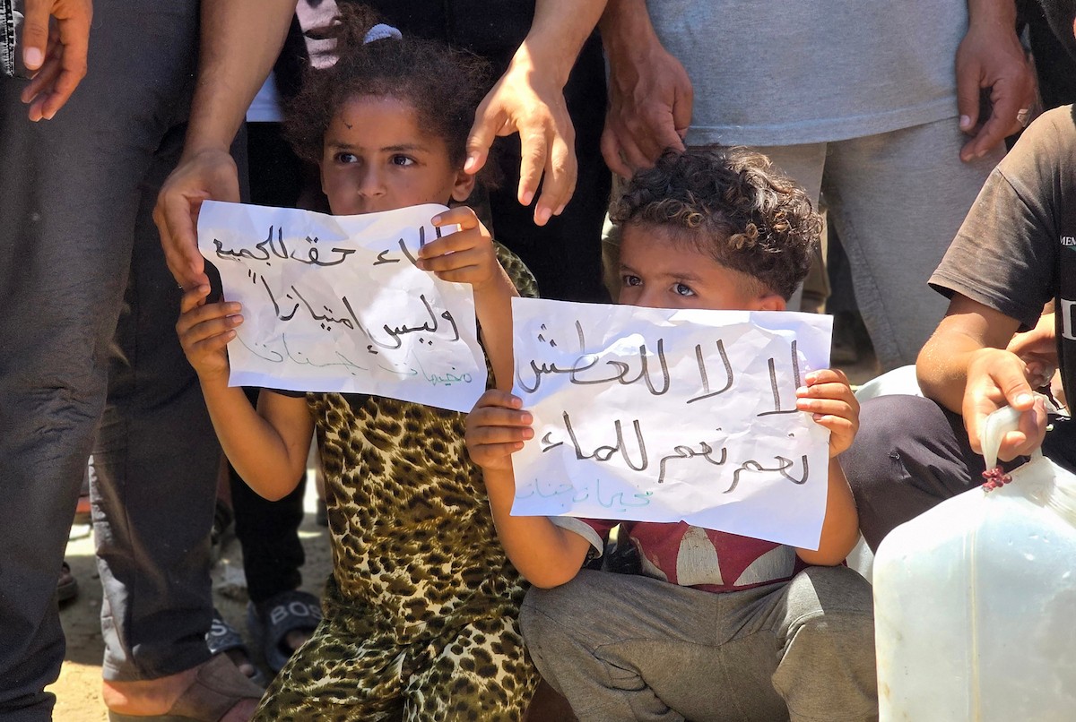فلسطينيون نازحون يحملون عبوات مياه فارغة خلال احتجاج للمطالبة بتوفير مياه شرب آمنة في خان يونس جنوب قطاع غزة، 25 مايو/أيار 2026. تصوير: طارق محمد
