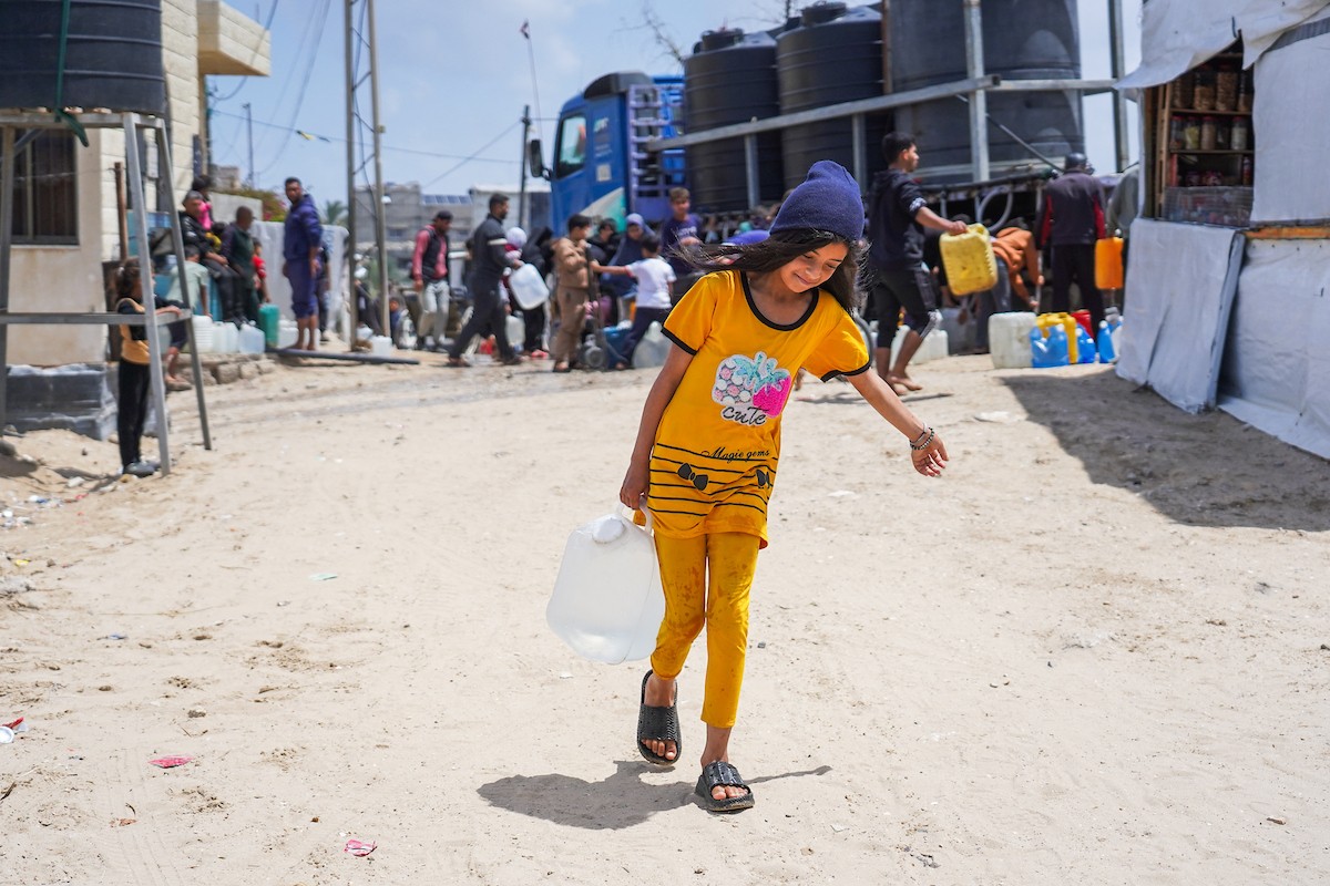يحاول فلسطينيون نازحون، بينهم أطفال ونساء، جلب الماء من صهريج مياه متنقل في منطقة المواصي بخان يونس، جنوب قطاع غزة، 5 مايو/أيار 2026( صورة: رمزي أبو عامر)