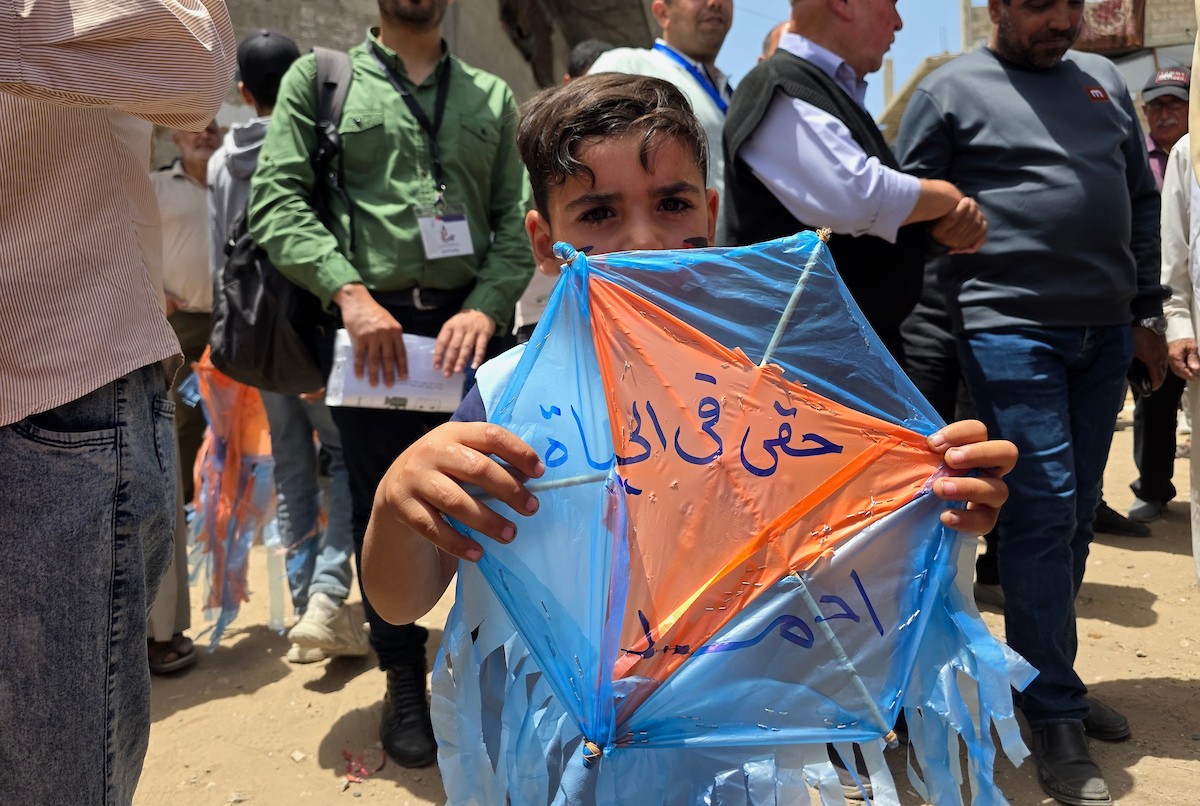 أطفال فلسطينيون يُعدّون ويُحلّقون طائرات ورقية ملوّنة كُتبت عليها آمالهم وأحلامهم، خلال فعالية «سمائي، طائرتي الورقية» في خان يونس جنوب قطاع غزة، وسط مبانٍ مدمرة وأكوام من الركام، يوم 19 مايو/أيار 2026. تصوير: طارق محمد
