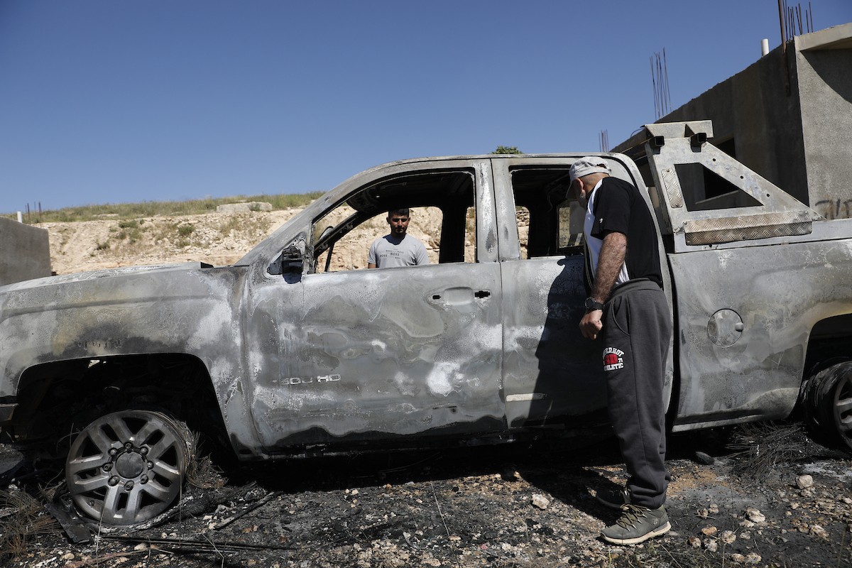 يتفقد فلسطينيون مركبةً تضررت بعد أن أضرم فيها مستوطنون إسرائيليون النار في وادي الرحيم قرب بلدة يطا، جنوب الخليل في الضفة الغربية، في الأول من مايو/أيار 2026.(صورة: مأمون وزواز)