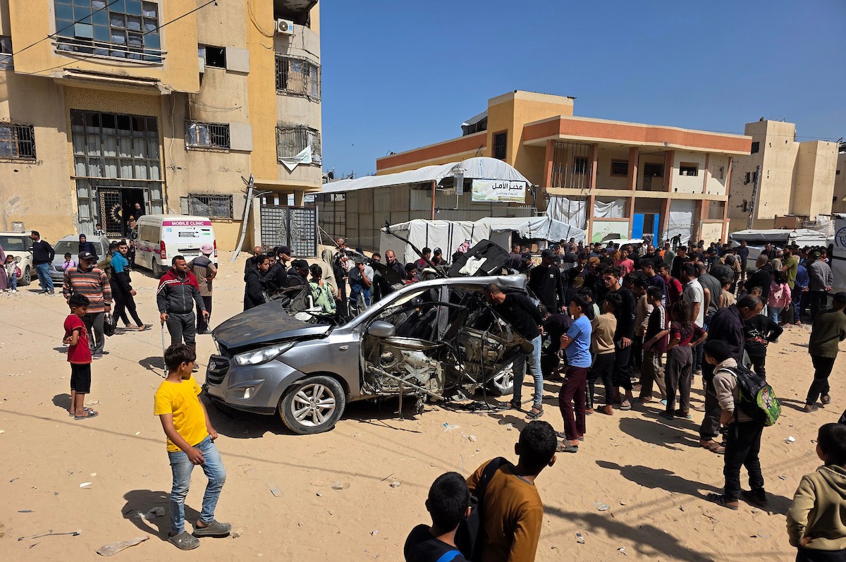 تُظهر الصورة فلسطينيين يتفقدون آثار غارة إسرائيلية استهدفت مركبة في خان يونس، جنوب قطاع غزة، حيث تحولت المركبة إلى حطام، فيما واصل الأهالي التجمع في المكان وسط حالة من الصدمة والغضب، 10 أيار/ مايو 2026.(صورة: طارق محمد)