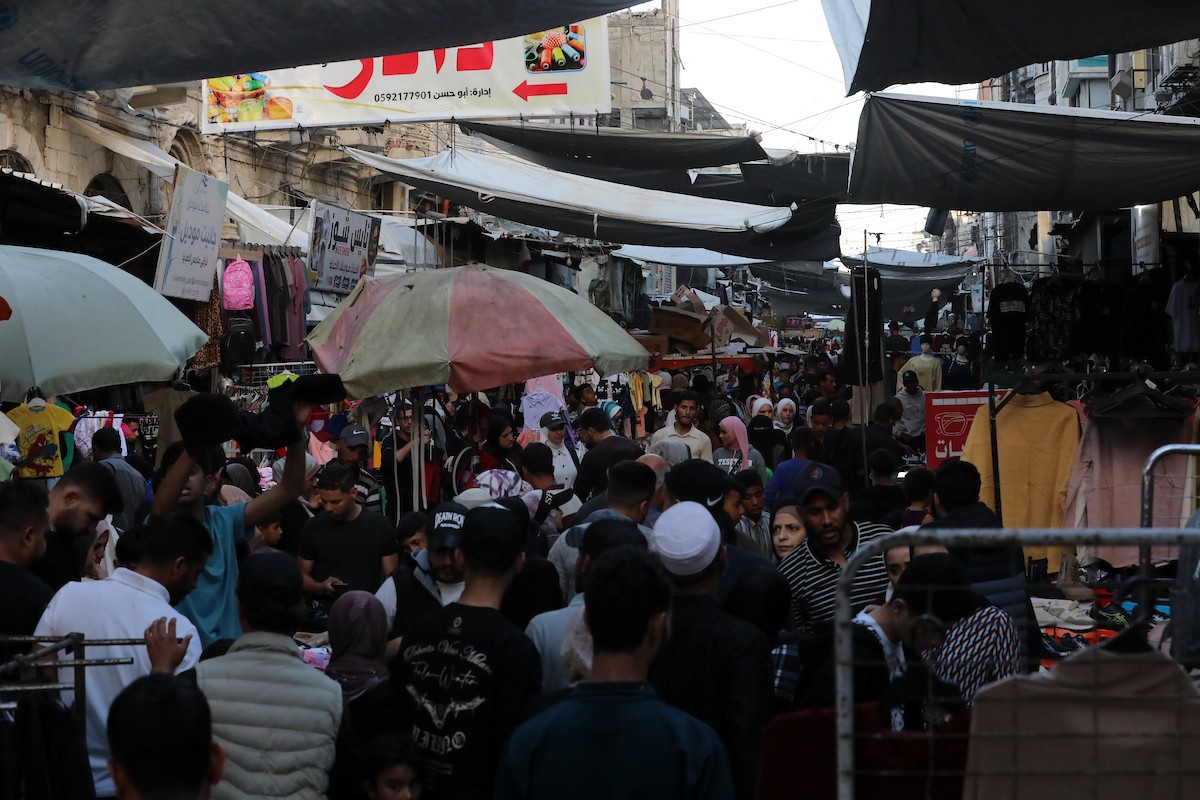 فلسطينيون يتجولون في سوق عمر المختار بمدينة غزة، حيث يعرض الباعة بضائعهم على أكشاك مؤقتة قبيل عيد الأضحى، وسط ضعف في الطلب وتراجع القدرة الشرائية، 25 مايو/أيار 2026. تصوير: بلال أسامة