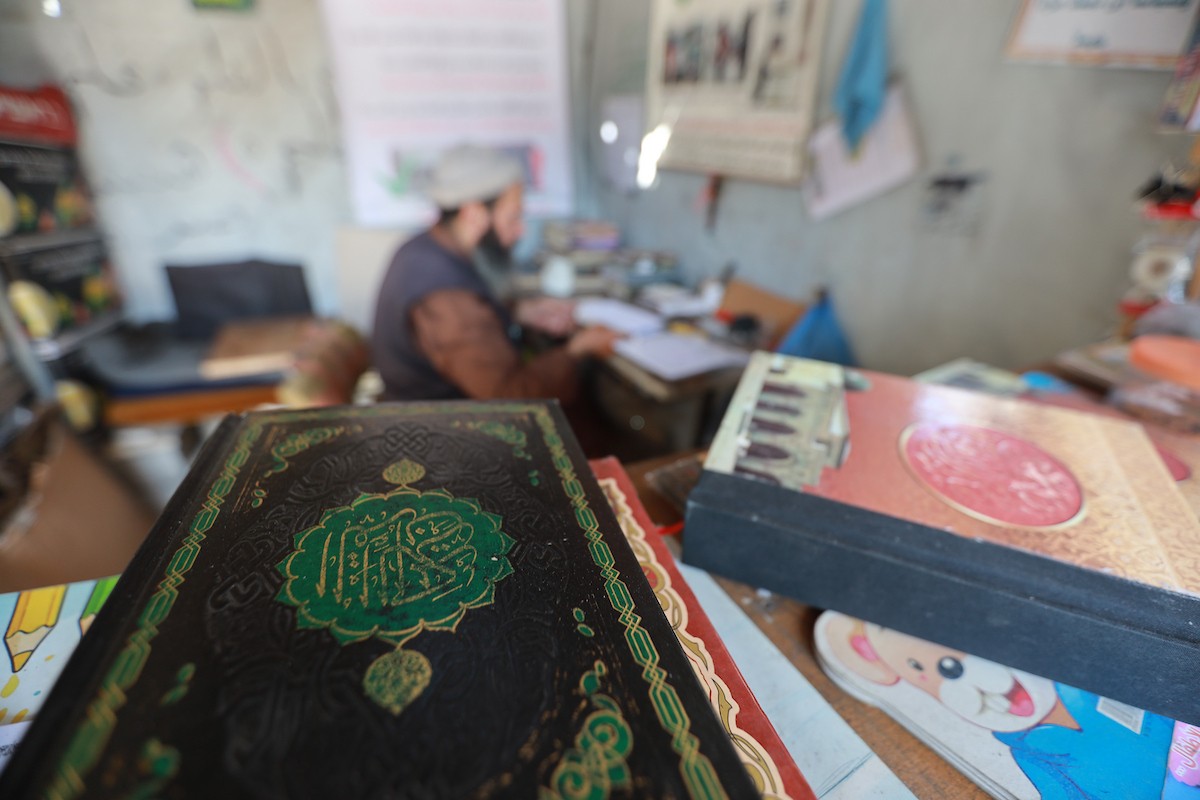 المسنّ الفلسطيني رفعت جبر يرمم نسخ تالفة من المصحف الشريف، عُثر عليها بين أنقاض المساجد والمنازل التي دُمّرت خلال الهجمات الإسرائيلية في مدينة غزة، 5 مايو/أيار 2026 (صورة: عمر أشتوي)