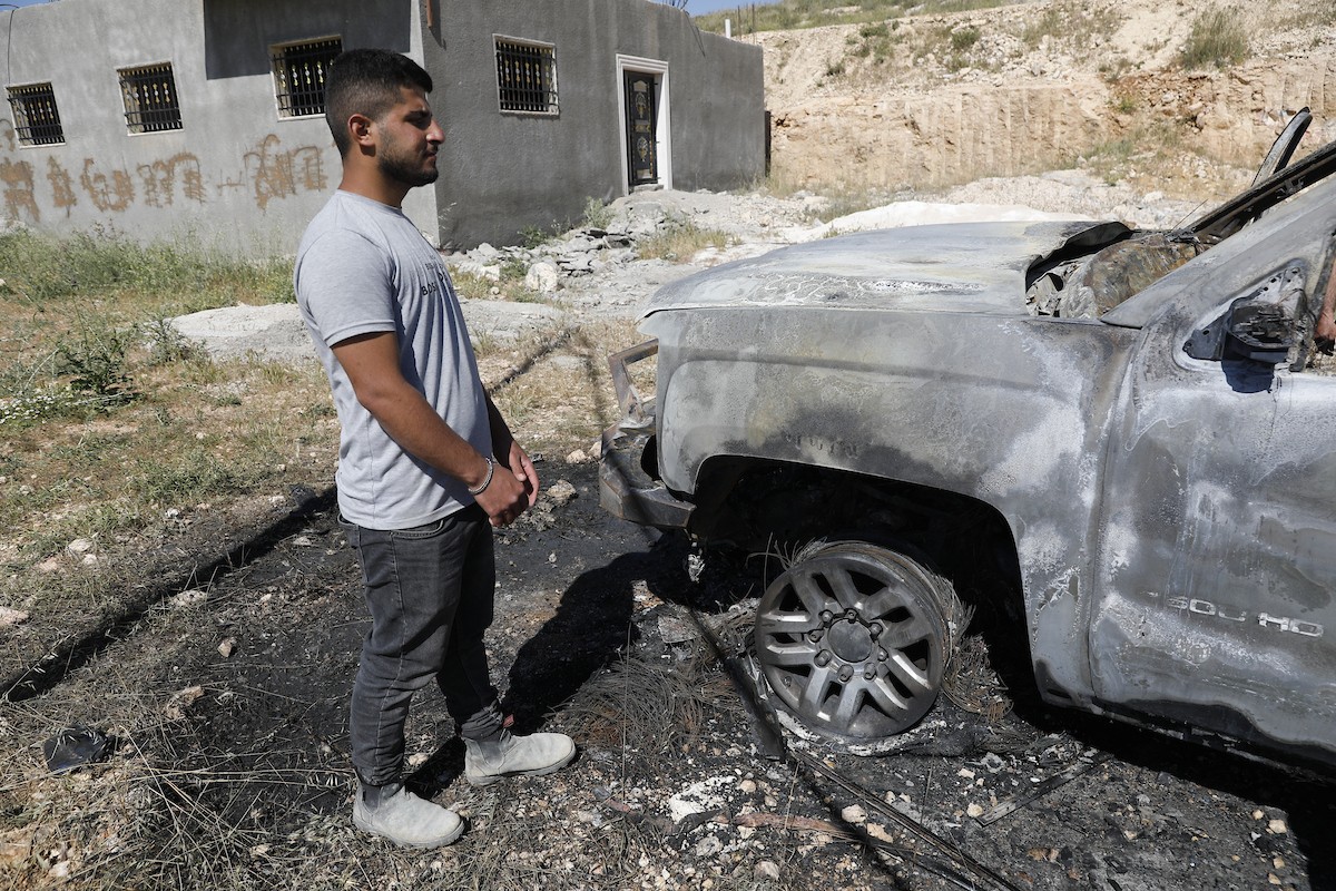 يتفقد فلسطينيون مركبةً تضررت بعد أن أضرم فيها مستوطنون إسرائيليون النار في وادي الرحيم قرب بلدة يطا، جنوب الخليل في الضفة الغربية، في الأول من مايو/أيار 2026.(صورة: مأمون وزواز)