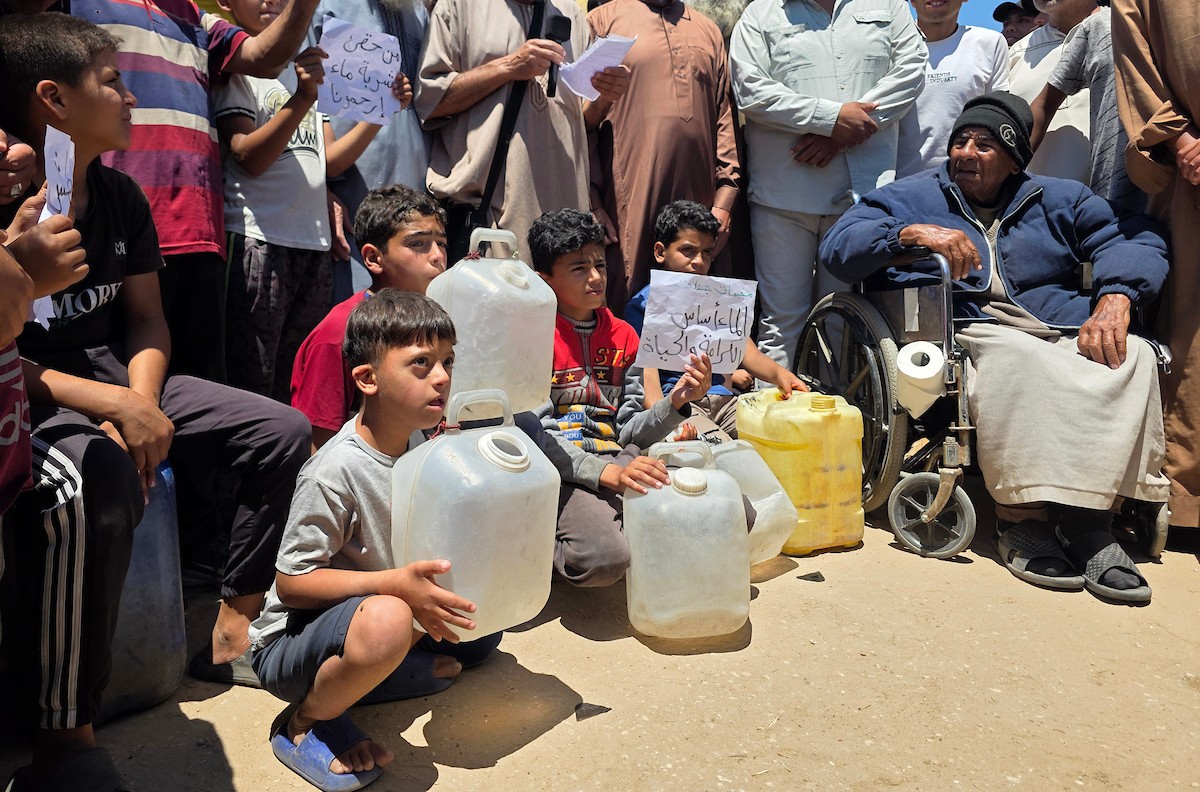 فلسطينيون نازحون يحملون عبوات مياه فارغة خلال احتجاج للمطالبة بتوفير مياه شرب آمنة في خان يونس جنوب قطاع غزة، 25 مايو/أيار 2026. تصوير: طارق محمد