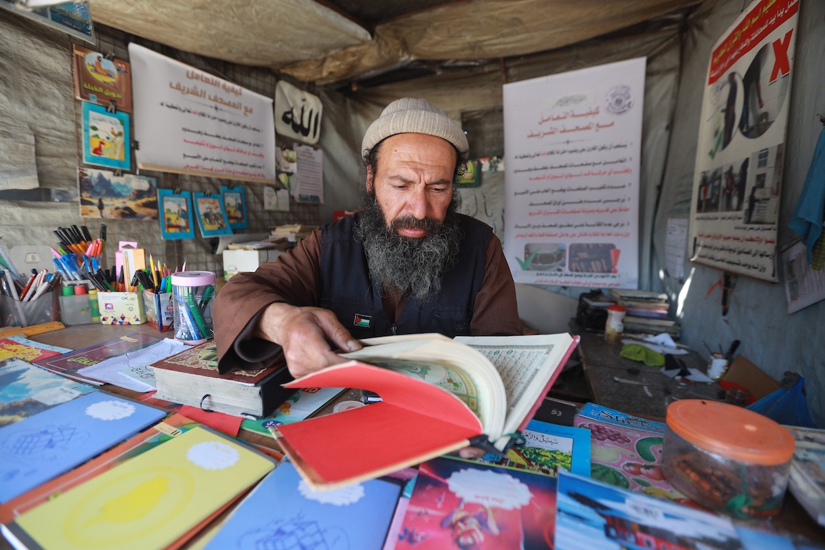 المسنّ الفلسطيني رفعت جبر يرمم نسخ تالفة من المصحف الشريف، عُثر عليها بين أنقاض المساجد والمنازل التي دُمّرت خلال الهجمات الإسرائيلية في مدينة غزة، 5 مايو/أيار 2026 (صورة: عمر أشتوي)