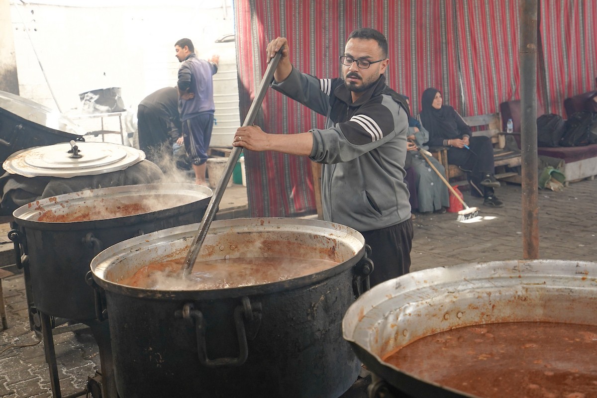 فلسطينيون نازحون، بينهم نساء وأطفال، يتجمعون لتلقي وجبات طعام من مطبخ خيري في مخيم النصيرات للاجئين وسط قطاع غزة، في 21 مايو/أيار 2026. الصورة: رمزي أبو عامر.