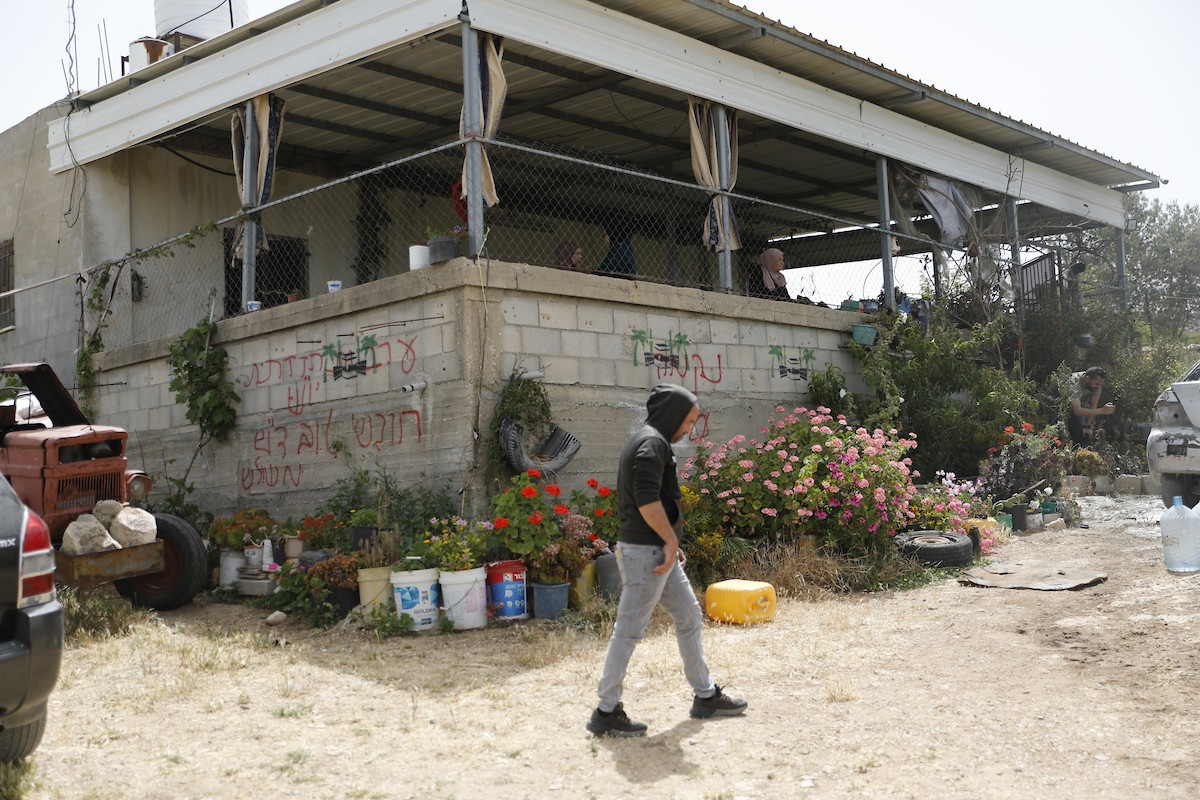 فلسطينيون يتفقدون أضرار هجوم للمستوطنين في بلدة صوريف شمال غرب الخليل، بعد إحراق مركبة وكتابة شعارات عنصرية على الجدران، 17 أيار/ مايو 2026.تصوير: مأمون وزواز