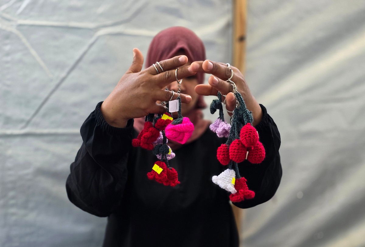 أرامل فلسطينيات يعملن على حياكة المشغولات الصوفية داخل خيمة في مخيم البركة للأيتام بمنطقة مواصي في خان يونس جنوب قطاع غزة، في 11 مايو/أيار 2026، سعياً منهن لتأمين دخل لإعالة أطفالهن بعد استشهاد أزواجهن في الحرب. (صورة: طارق محمد)