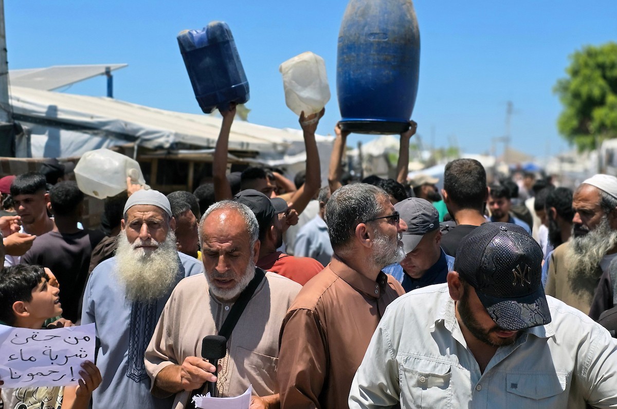 فلسطينيون نازحون يحملون عبوات مياه فارغة خلال احتجاج للمطالبة بتوفير مياه شرب آمنة في خان يونس جنوب قطاع غزة، 25 مايو/أيار 2026. تصوير: طارق محمد