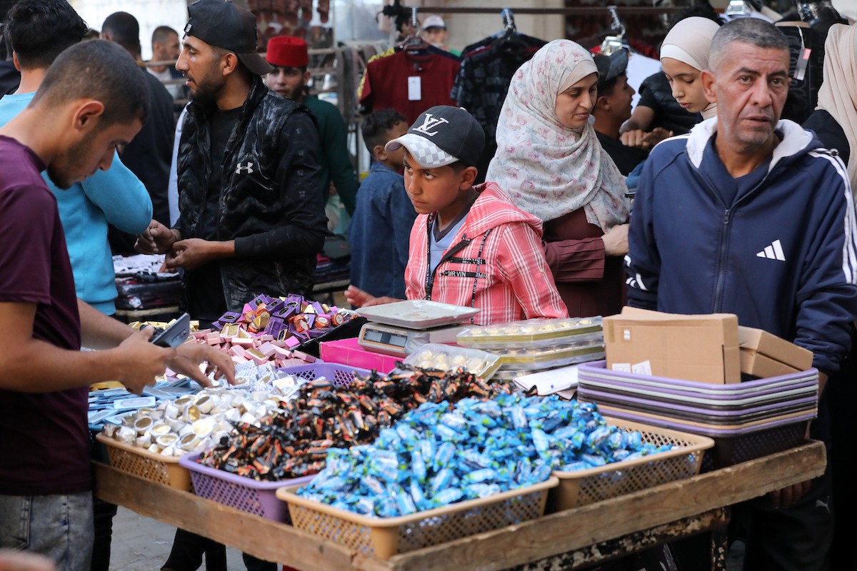 فلسطينيون يتجولون في سوق عمر المختار بمدينة غزة، حيث يعرض الباعة بضائعهم على أكشاك مؤقتة قبيل عيد الأضحى، وسط ضعف في الطلب وتراجع القدرة الشرائية، 25 مايو/أيار 2026. تصوير: بلال أسامة