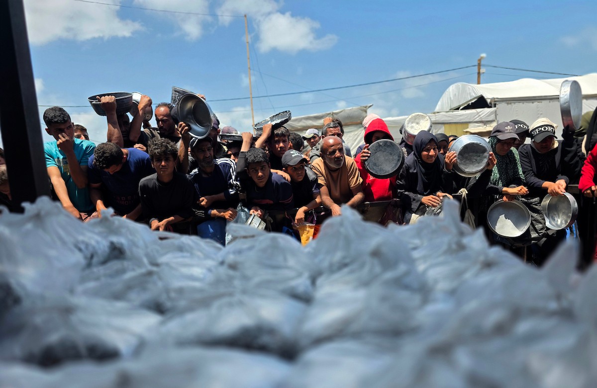 تُظهر الصورة نازحين فلسطينيين متجمعين حول نقطة توزيع طعام في خان يونس جنوب قطاع غزة، حيث ينتظر رجال ونساء وأطفال الحصول على وجبات من مطبخ خيري وسط ظروف إنسانية صعبة،  8 مايو/أيار 2026. عدسة : طارق محمد