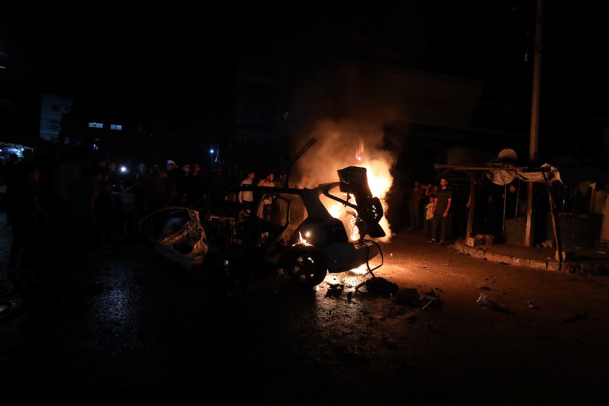 فلسطينيون يعملون على إخماد حريق اندلع في سيارة استُهدفت بغارة إسرائيلية في حي الرمال بمدينة غزة، الجمعة 15 مايو/أيار 2026. صورة: عمر أشتوي.