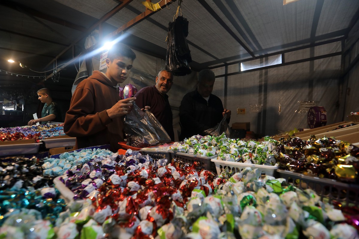 فلسطينيون يتجولون في سوق عمر المختار بمدينة غزة، حيث يعرض الباعة بضائعهم على أكشاك مؤقتة قبيل عيد الأضحى، وسط ضعف في الطلب وتراجع القدرة الشرائية، 25 مايو/أيار 2026. تصوير: بلال أسامة