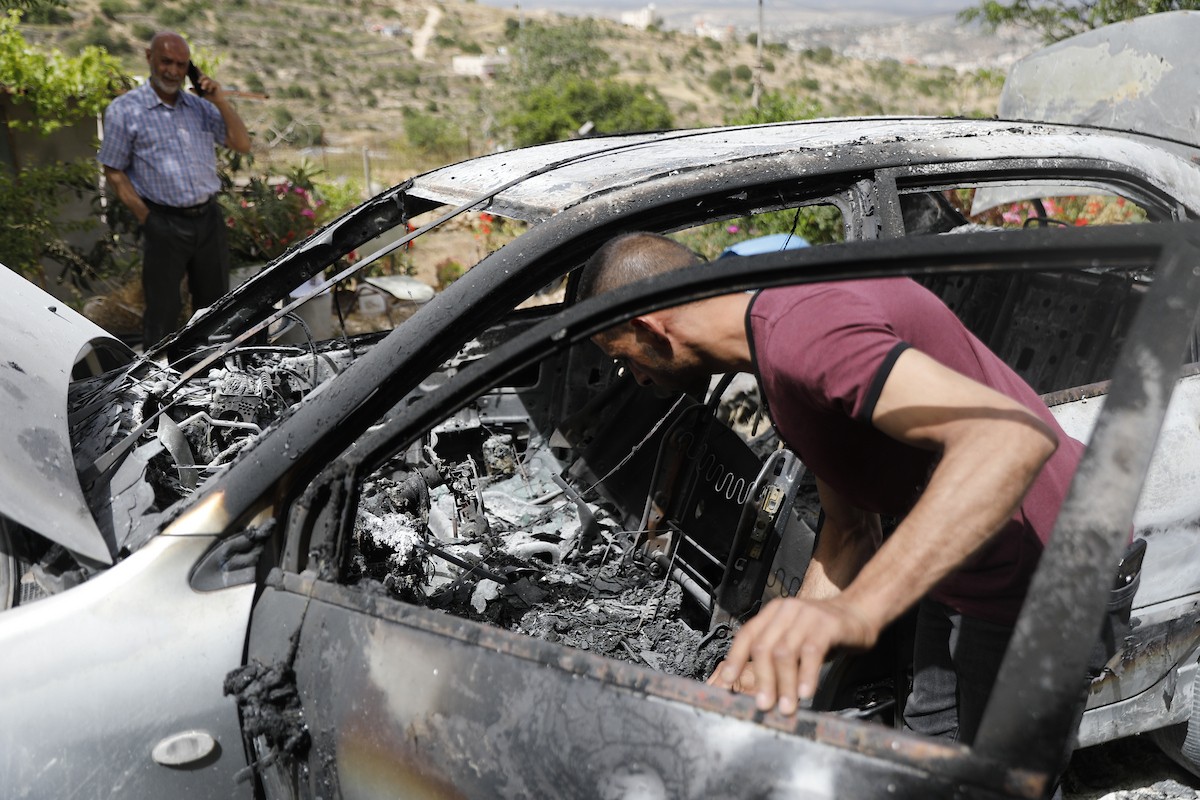 فلسطينيون يتفقدون أضرار هجوم للمستوطنين في بلدة صوريف شمال غرب الخليل، بعد إحراق مركبة وكتابة شعارات عنصرية على الجدران، 17 أيار/ مايو 2026.تصوير: مأمون وزواز