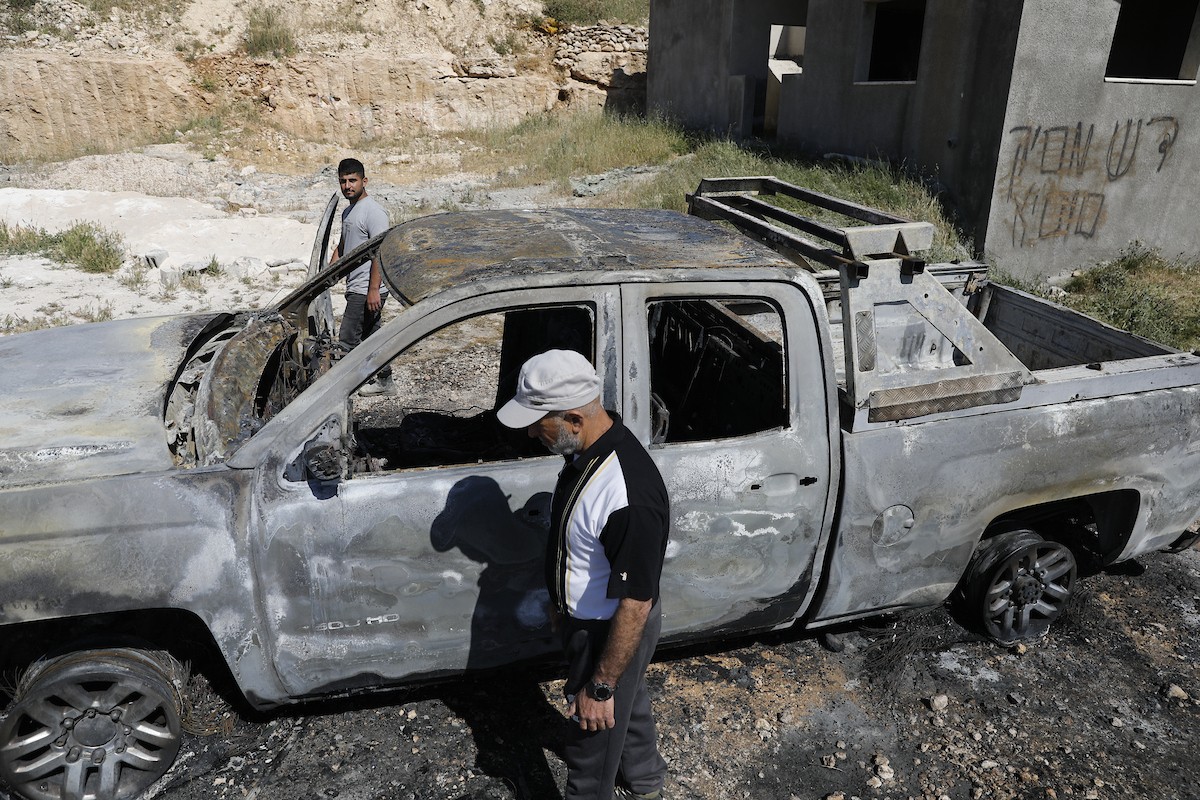 يتفقد فلسطينيون مركبةً تضررت بعد أن أضرم فيها مستوطنون إسرائيليون النار في وادي الرحيم قرب بلدة يطا، جنوب الخليل في الضفة الغربية، في الأول من مايو/أيار 2026.(صورة: مأمون وزواز)