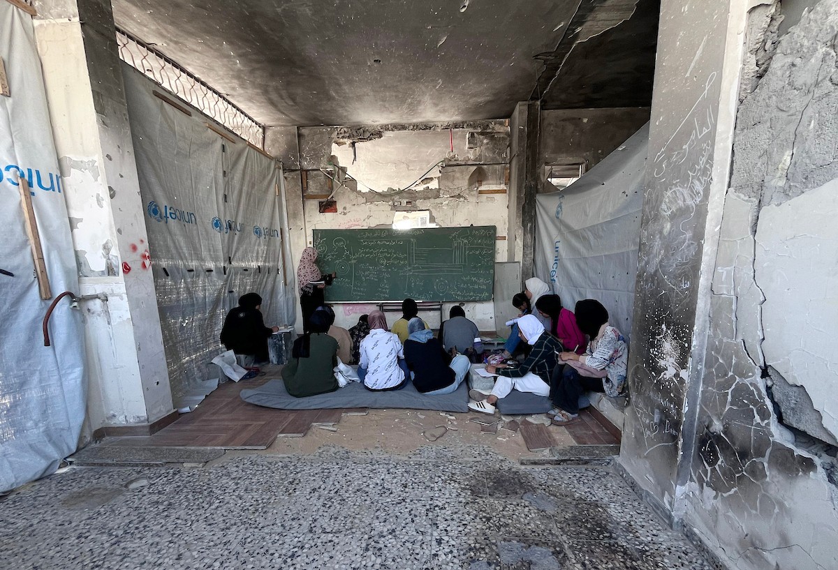 طلاب فلسطينيون يتلقون دروسهم داخل منزل مدمر شرق جباليا شمال قطاع غزة، مستخدمين الحجارة بدل المقاعد، بعد سنوات من الانقطاع عن التعليم بسبب الحرب، 17 أيار/ مايو 2026.تصوير: مطر الزاق