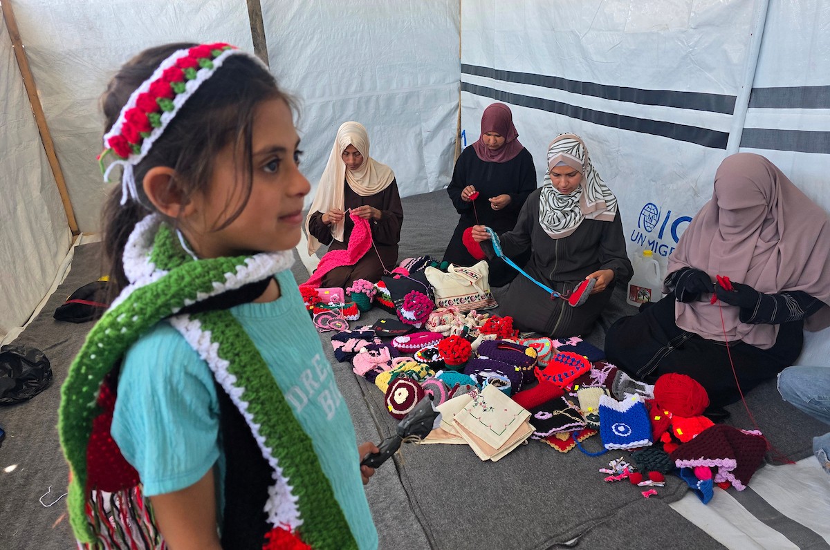 أرامل فلسطينيات يعملن على حياكة المشغولات الصوفية داخل خيمة في مخيم البركة للأيتام بمنطقة مواصي في خان يونس جنوب قطاع غزة، في 11 مايو/أيار 2026، سعياً منهن لتأمين دخل لإعالة أطفالهن بعد استشهاد أزواجهن في الحرب. (صورة: طارق محمد)