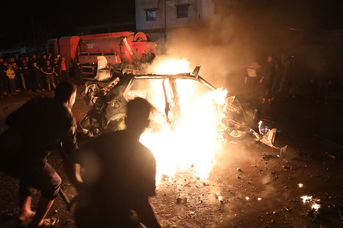 فلسطينيون يعملون على إخماد حريق اندلع في سيارة استُهدفت بغارة إسرائيلية في حي الرمال بمدينة غزة، الجمعة 15 مايو/أيار 2026. صورة: عمر أشتوي.