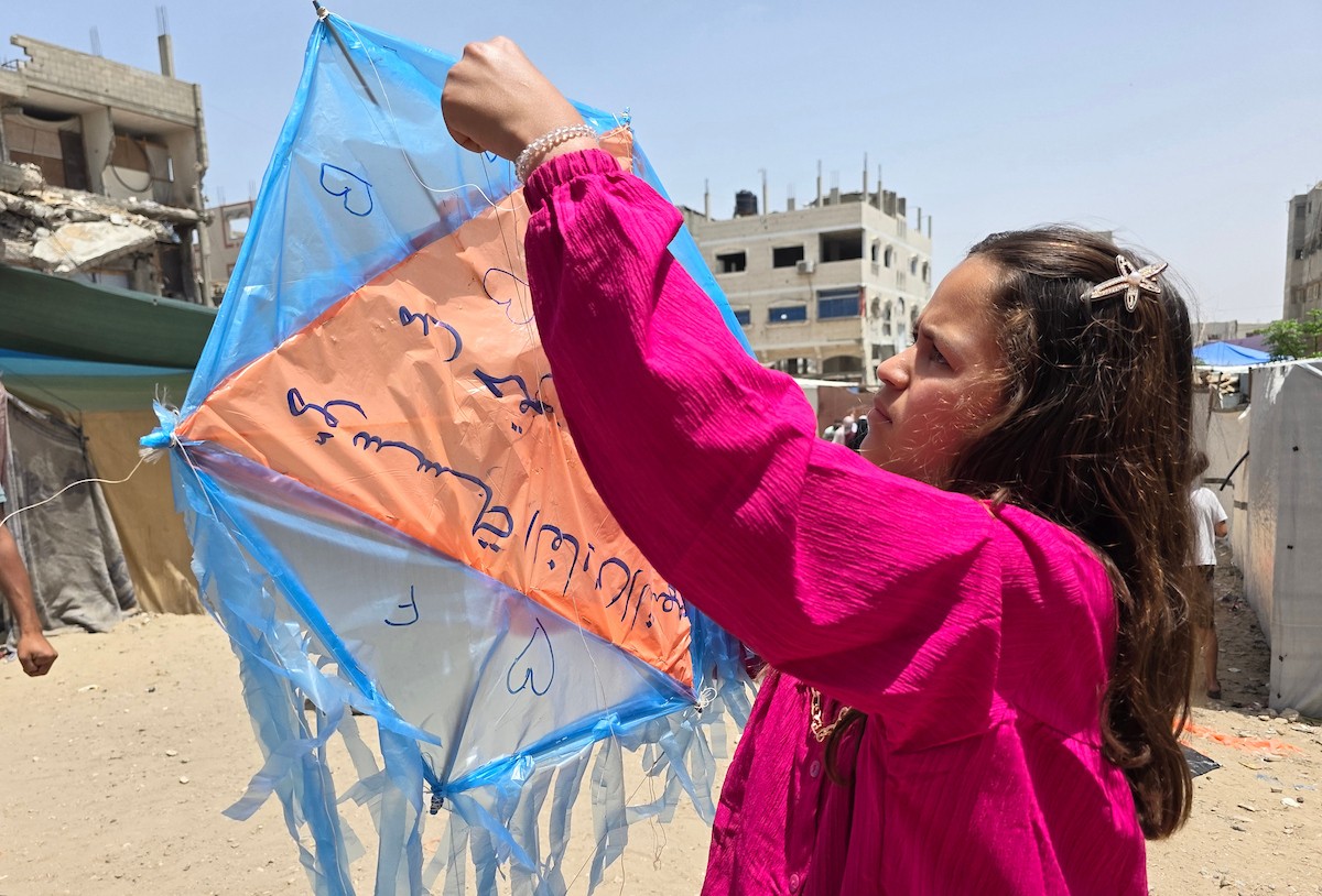 أطفال فلسطينيون يُعدّون ويُحلّقون طائرات ورقية ملوّنة كُتبت عليها آمالهم وأحلامهم، خلال فعالية «سمائي، طائرتي الورقية» في خان يونس جنوب قطاع غزة، وسط مبانٍ مدمرة وأكوام من الركام، يوم 19 مايو/أيار 2026. تصوير: طارق محمد