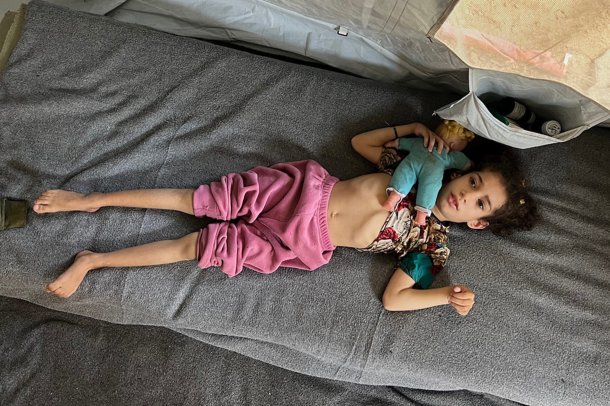 الطفلة داليا الزويدي تتلقى الرعاية من والديها داخل خيمة نزوحهم في مخيم النصيرات، تعاني داليا من نقص الأكسجين وسوء التغذية وسط تدهور الأوضاع الصحية ونقص الغذاء والدواء في القطاع، 10 أيار/ مايو 2026.(صورة: يوسف أبو وطفة)