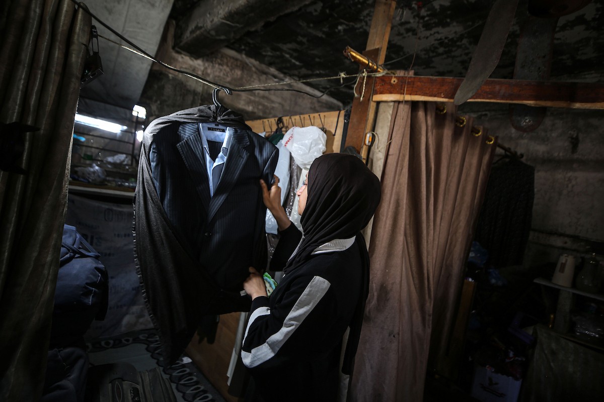 لينا مقداد، عروس فلسطينية، تنظر إلى صور ومقتنيات والدها بجانب فستان زفافها داخل مدرسة  تحُِّلت إلى مأوى للنازحين، في حي الشيخ رضوان بمدينة غزة، في 3 مايو/أيار 2026. فقدت مقداد والدها، عماد مقداد، في هجمات إسرائيلية على غزة قبل أسبوعين من زفافها