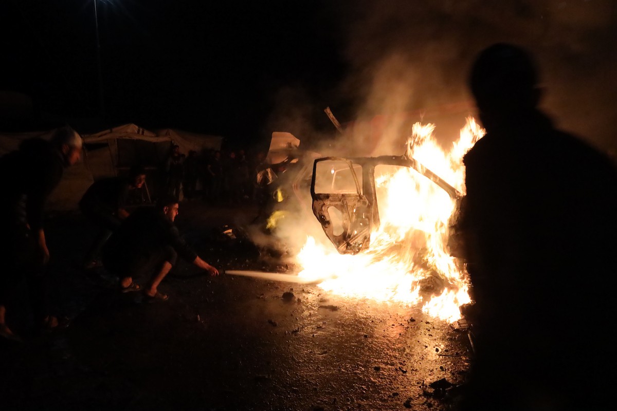 فلسطينيون يعملون على إخماد حريق اندلع في سيارة استُهدفت بغارة إسرائيلية في حي الرمال بمدينة غزة، الجمعة 15 مايو/أيار 2026. صورة: عمر أشتوي.