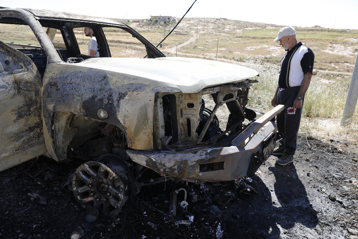 يتفقد فلسطينيون مركبةً تضررت بعد أن أضرم فيها مستوطنون إسرائيليون النار في وادي الرحيم قرب بلدة يطا، جنوب الخليل في الضفة الغربية، في الأول من مايو/أيار 2026.(صورة: مأمون وزواز)