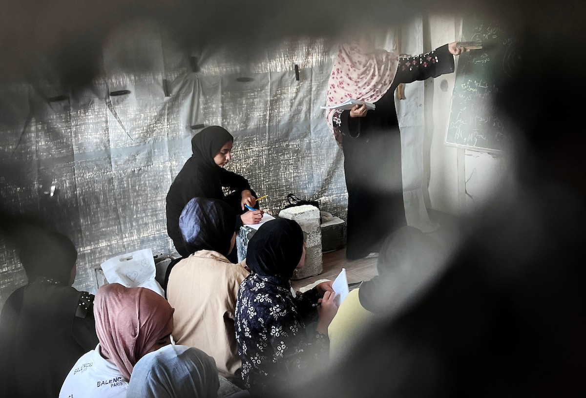 طلاب فلسطينيون يتلقون دروسهم داخل منزل مدمر شرق جباليا شمال قطاع غزة، مستخدمين الحجارة بدل المقاعد، بعد سنوات من الانقطاع عن التعليم بسبب الحرب، 17 أيار/ مايو 2026.تصوير: مطر الزاق