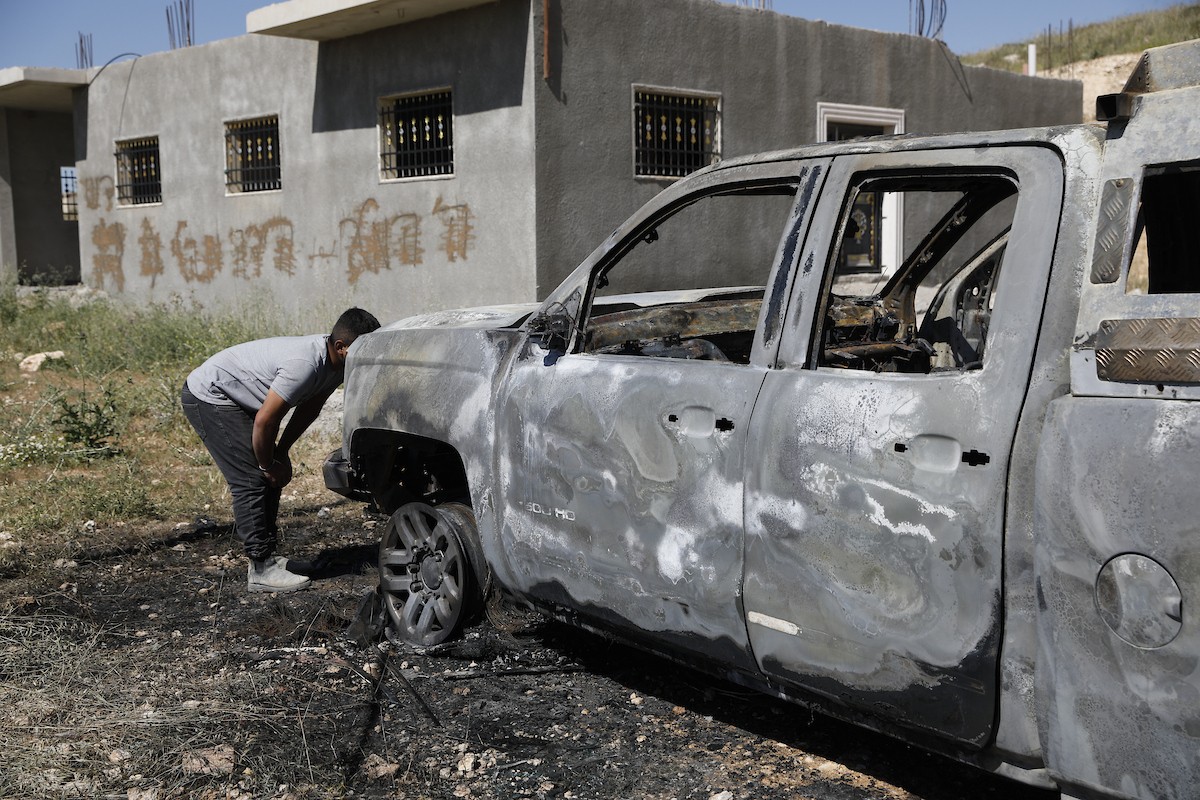 يتفقد فلسطينيون مركبةً تضررت بعد أن أضرم فيها مستوطنون إسرائيليون النار في وادي الرحيم قرب بلدة يطا، جنوب الخليل في الضفة الغربية، في الأول من مايو/أيار 2026.(صورة: مأمون وزواز)