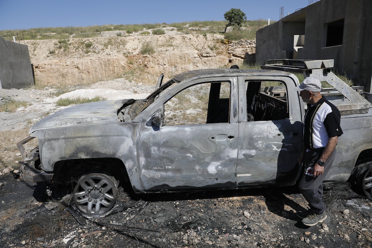 يتفقد فلسطينيون مركبةً تضررت بعد أن أضرم فيها مستوطنون إسرائيليون النار في وادي الرحيم قرب بلدة يطا، جنوب الخليل في الضفة الغربية، في الأول من مايو/أيار 2026.(صورة: مأمون وزواز)