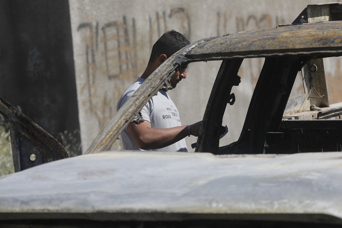 يتفقد فلسطينيون مركبةً تضررت بعد أن أضرم فيها مستوطنون إسرائيليون النار في وادي الرحيم قرب بلدة يطا، جنوب الخليل في الضفة الغربية، في الأول من مايو/أيار 2026.(صورة: مأمون وزواز)