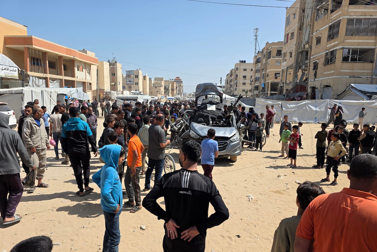 تُظهر الصورة فلسطينيين يتفقدون آثار غارة إسرائيلية استهدفت مركبة في خان يونس، جنوب قطاع غزة، حيث تحولت المركبة إلى حطام، فيما واصل الأهالي التجمع في المكان وسط حالة من الصدمة والغضب، 10 أيار/ مايو 2026.(صورة: طارق محمد)