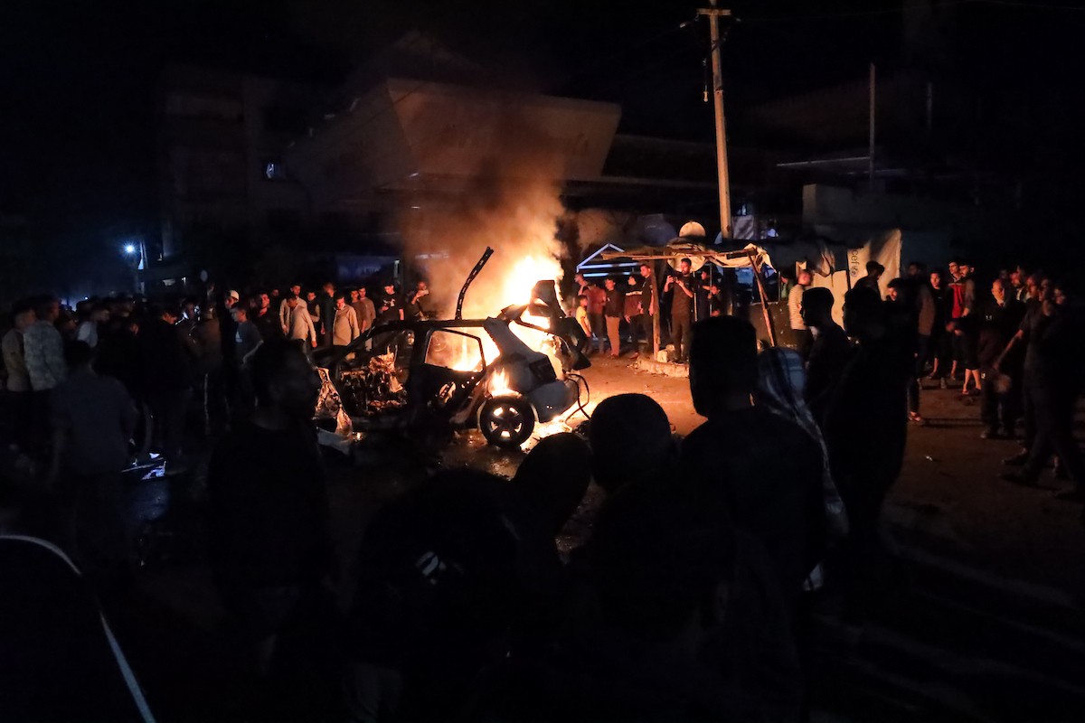 فلسطينيون يعملون على إخماد حريق اندلع في سيارة استُهدفت بغارة إسرائيلية في حي الرمال بمدينة غزة، الجمعة 15 مايو/أيار 2026. صورة: عمر أشتوي.
