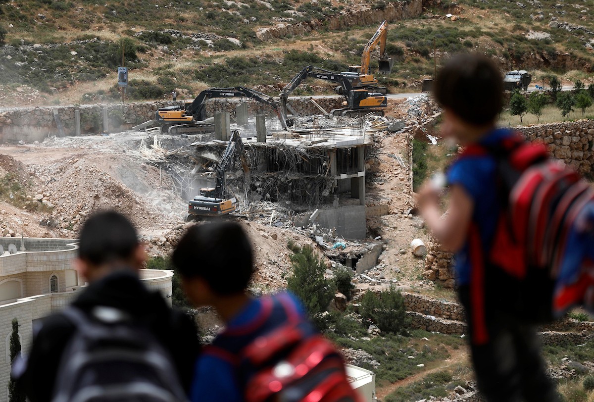 جرافات إسرائيلية تهدم مبنى سكنياً فلسطينياً قيد الإنشاء في بلدة الولجة غرب بيت لحم، في 18 مايو/أيار 2026، وسط انتشار قوات الاحتلال وتجمّع الأهالي لمتابعة عملية الهدم. الصورة: مأمون وزواز
