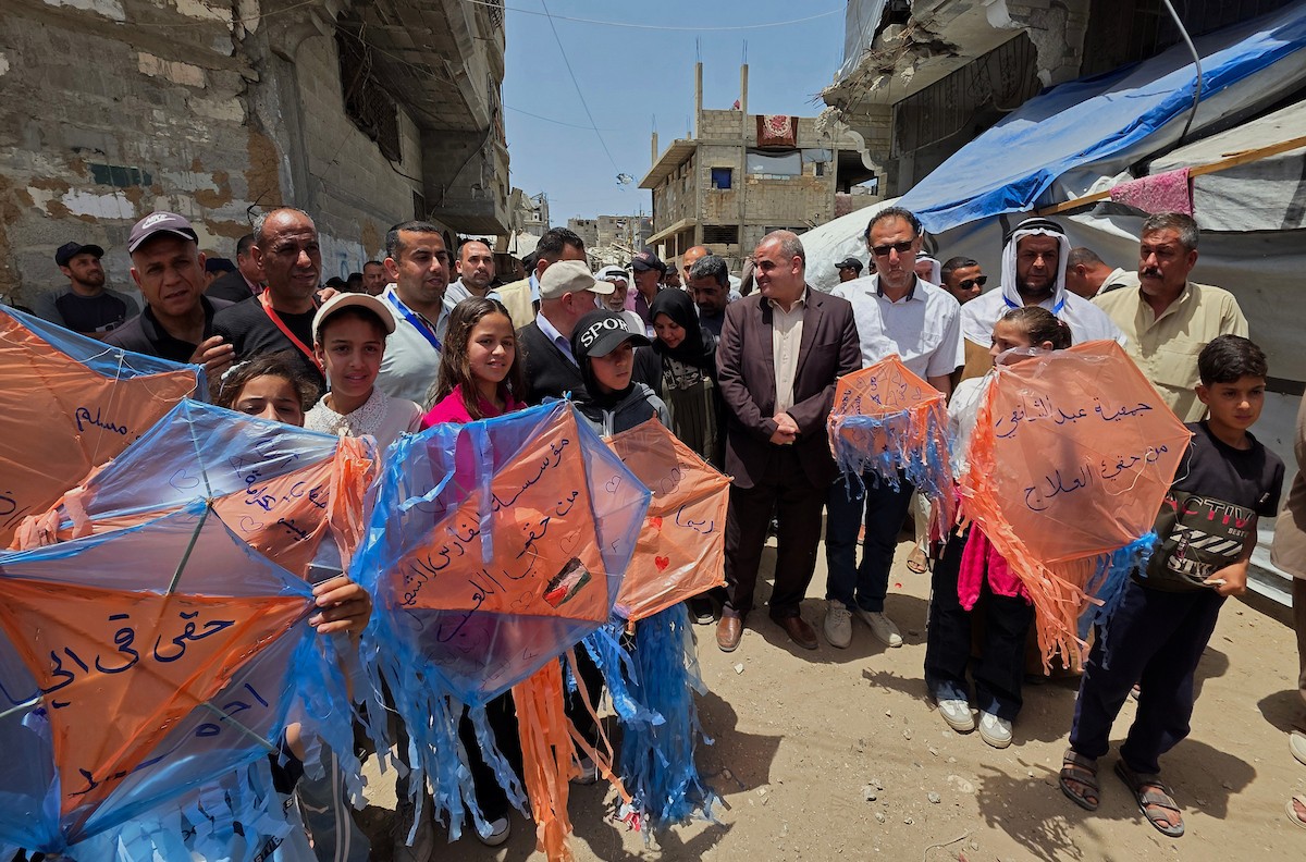 أطفال فلسطينيون يُعدّون ويُحلّقون طائرات ورقية ملوّنة كُتبت عليها آمالهم وأحلامهم، خلال فعالية «سمائي، طائرتي الورقية» في خان يونس جنوب قطاع غزة، وسط مبانٍ مدمرة وأكوام من الركام، يوم 19 مايو/أيار 2026. تصوير: طارق محمد