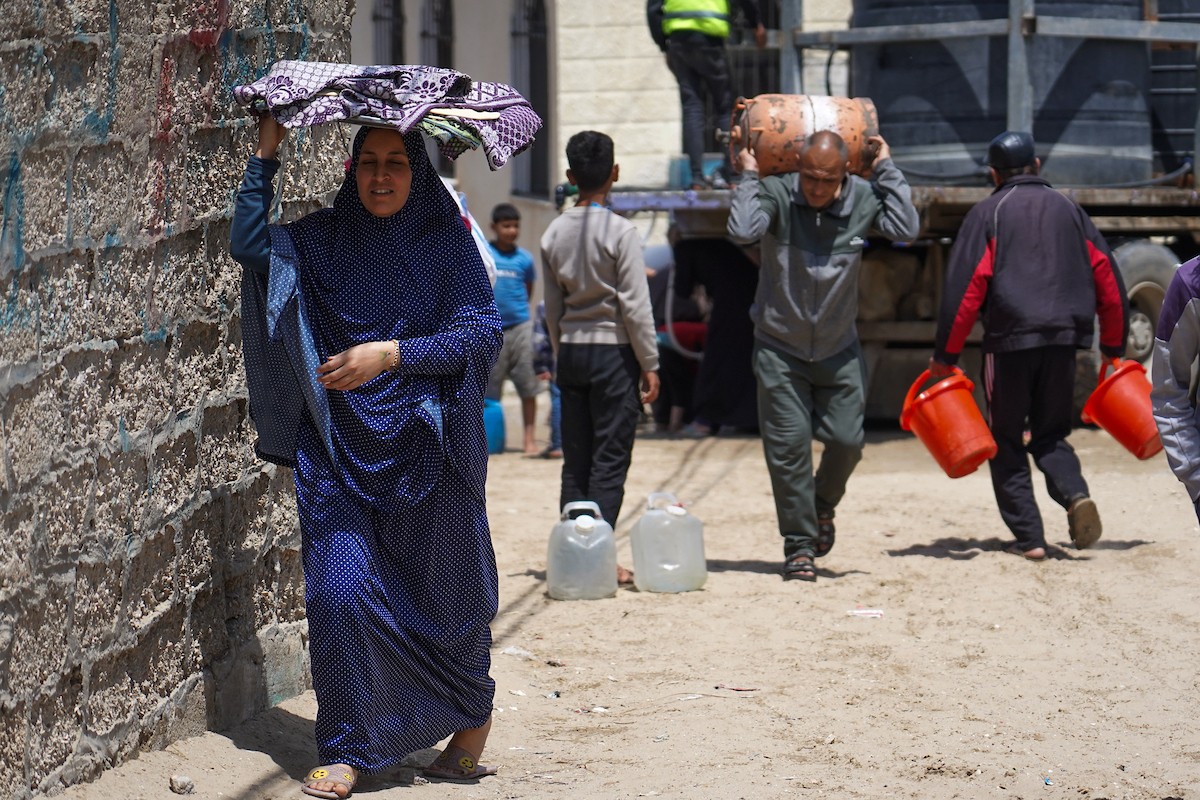 يحاول فلسطينيون نازحون، بينهم أطفال ونساء، جلب الماء من صهريج مياه متنقل في منطقة المواصي بخان يونس، جنوب قطاع غزة، 5 مايو/أيار 2026( صورة: رمزي أبو عامر)