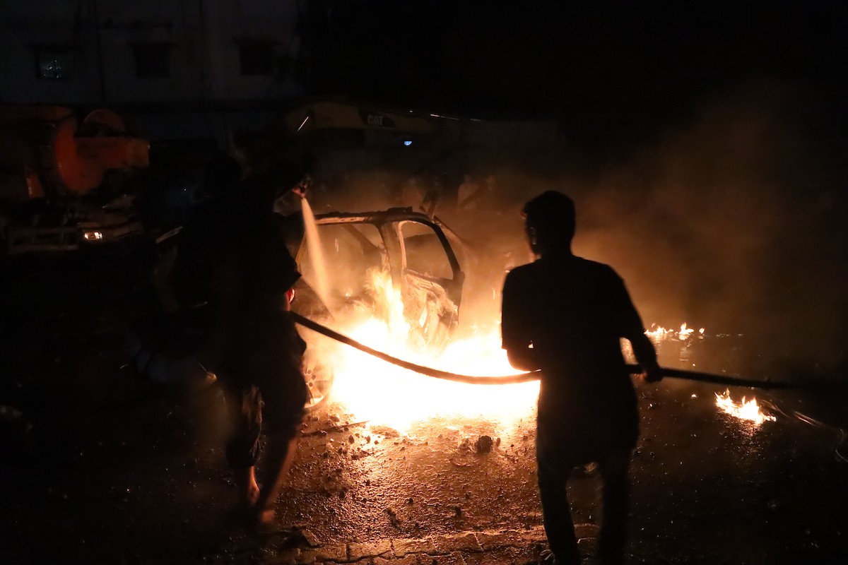 فلسطينيون يعملون على إخماد حريق اندلع في سيارة استُهدفت بغارة إسرائيلية في حي الرمال بمدينة غزة، الجمعة 15 مايو/أيار 2026. صورة: عمر أشتوي.